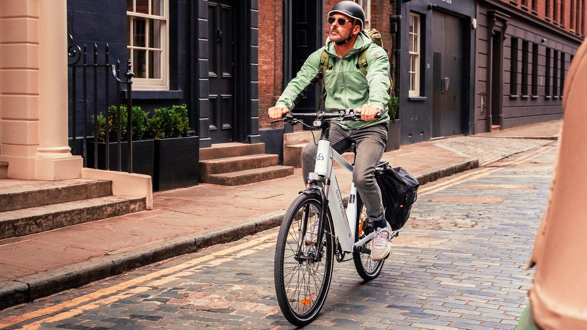 Man riding a commuter electric bike on a cobbled UK city street, representing one of the best adult e-bikes for urban commuting in 2026