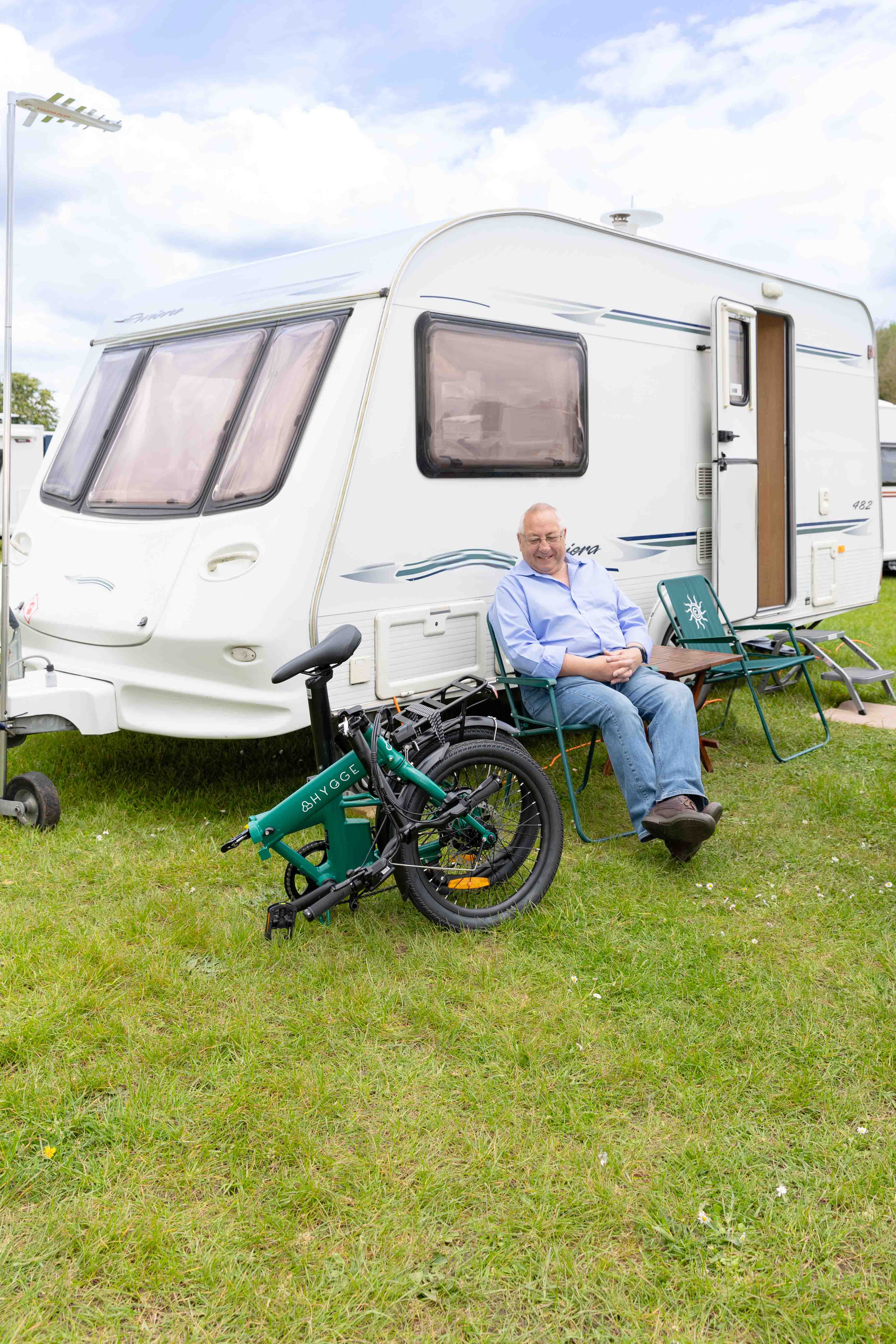 A man sitting outside his caravan with a Hygge Virum folding e-bike, sharing his positive experience on the road