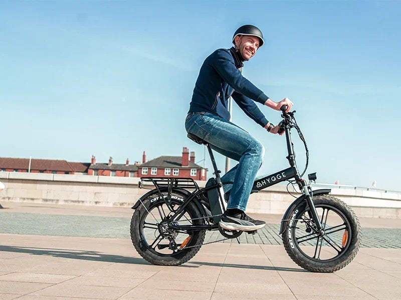 Rider cycling a Hygge folding electric bike on a paved waterfront route, showcasing its compact design and everyday commuting capability.